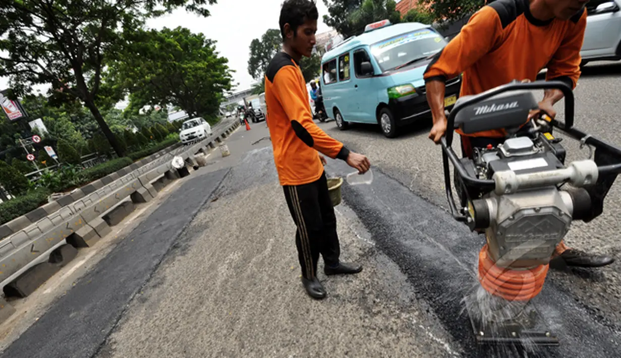 Sejumlah pekerja melakukan perbaikan dengan mengaspal jalan berlubang di Jalan Kramat Raya, Jakarta, Rabu (25/2/2015). Perbaikan jalan rusak pascabanjir terus dikebut Dinas Pekerjaan Umum (DPU) DKI Jakarta. (Liputan6.com/Faizal Fanani) 