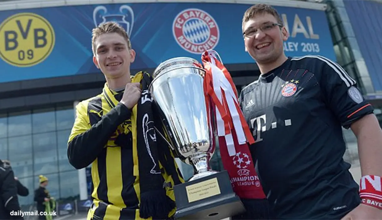 Dua orang suporter Borussia Dortmund dan Bayern Muencehen memegang replika tropi Liga Champions