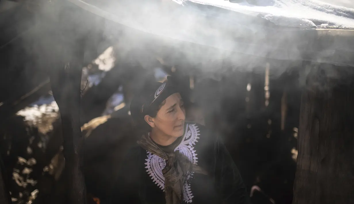 Seorang wanita berdiri di luar oven saat dia bersiap untuk memanggang roti untuk keluarganya di desa Amazigh Timahdite di Atlas Tengah, dekat Azrou, Maroko  (4/12/2021). (AP Photo/Mosa'ab Elshamy)