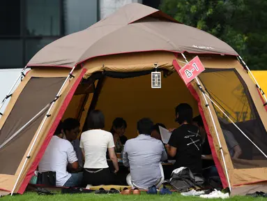 Foto 11 September 2018, karyawan perusahaan bekerja di dalam tenda kemah di halaman luar gedung kantor di Tokyo. Beberapa kantor di Jepang membebaskan pegawainya untuk bekerja di mana saja, mulai dari tenda hingga tempat karaoke. (Toshifumi KITAMURA/AFP)