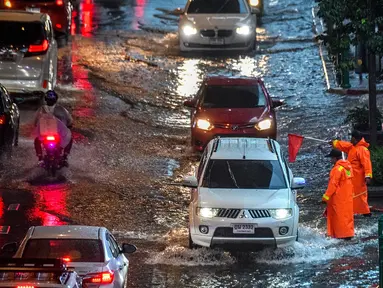 Petugas keamanan mengatur lalu lintas di jalan yang banjir saat hujan deras di Bangkok (23/9/2020). (AFP/Mladen Antonov)
