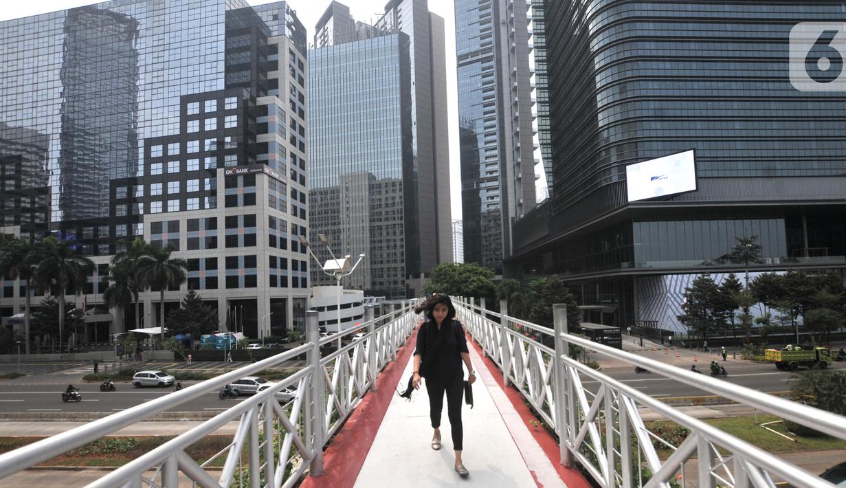 Pejalan kaki melintas di jembatan penyeberangan orang (JPO) yang tidak beratap di jalan Sudirman, Jakarta, Rabu (6/11/2019). Pemprov DKI melalui Dinas Bina Marga mencopot atap JPO Sudirman agar pejalan kaki dapat menikmati pemandangan gedung-gedung pencakar langit. (merdeka.com/Iqbal Nugroho)
