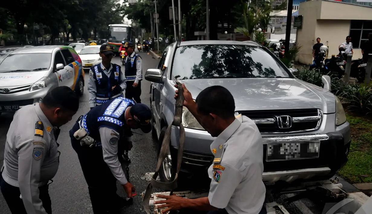 Petugas Dishub saat mengangkut mobil yang parkir sembarangan, Jakarta, Senin (12/1/2015). (Liputan6.com/Johan Tallo)