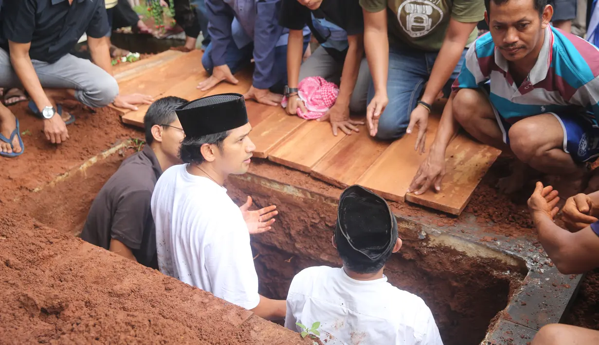 Sebelum jenazah diurug dengan tanah, suami Ririn Ekawati itu tampak melantunkan iqomah. [Foto: Adrian Putra/Fimela.com]