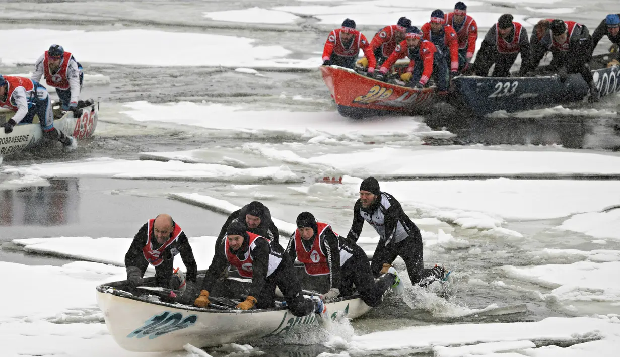 Tim Latulippe dilewati oleh Tony Allaire (belakang) bergerak melalui air es pada perlombaan kano es Karnaval Musim Dingin Quebec melintasi Sungai St. Lawrence di Kota Quebec, Kanada, 5 Februari 2023. (Jacques Boissinot/The Canadian Press via AP)
