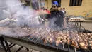 Relawan memanggang sate daging untuk hidangan buka puasa massal pada hari ke-15 bulan suci Ramadhan di pinggiran Matariya, timur laut Kairo, Mesir, 16 April 2022. (Khaled DESOUKI/AFP)