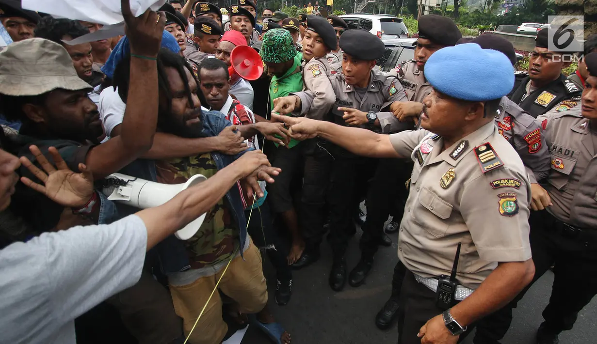 Polisi berusaha mengamankan aksi massa FRI-WP dan AMP di Jalan Medan Merdeka Barat, Jakarta, Selasa (15/8). Aksi tersebut menuntut agar pemerintah memberikan kebebasan dan hak menentukan nasib sendiri bagi rakyat Papua. (Liputan6.com/Immanuel Antonius)