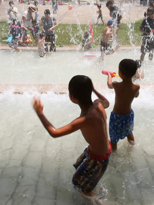 Dua orang anak bermain air di sebuah taman di Tokyo, Jepang, (16/7). Badan Meteorologi mengatakan gelombang panas terus berlanjut di wilayah metro ketika suhu naik mencapai 35 derajat Celcius (95 derajat Fahrenheit). (AP Photo/Koji Sasahara)