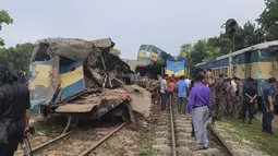 Orang-orang berkumpul di dekat gerbong kereta yang rusak parah setelah dua kereta yang melaju bertabrakan di distrik Brahmanbaria, 82 kilometer (51 mil) timur ibukota, Dhaka, Bangladesh, Selasa (12/11/2019). Sekitar 16 orang tewas dan 60 lainnya terluka akibat kecelakaan tersebut. (AP Photo)