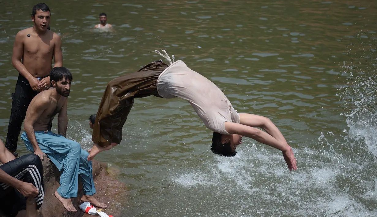 Sejumlah pria bermain di sungai saat siang hari saat Ramadan di Islamabad, Pakistan, Senin (5/6). Suhu di Pakistan pada siang hari mencapai 43 derajat celcius. (AFP PHOTO / AAMIR QURESHI)