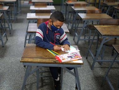 Sebastian (7) mengikuti kelas matematika sendirian pada hari pertama kembali ke sekolah tatap muka sejak dimulainya pembatasan pandemi COVID-19 di Sekolah Andres Bello, Caracas, Venezuela, 25 Oktober 2021. (AP Photo/Ariana Cubillos)