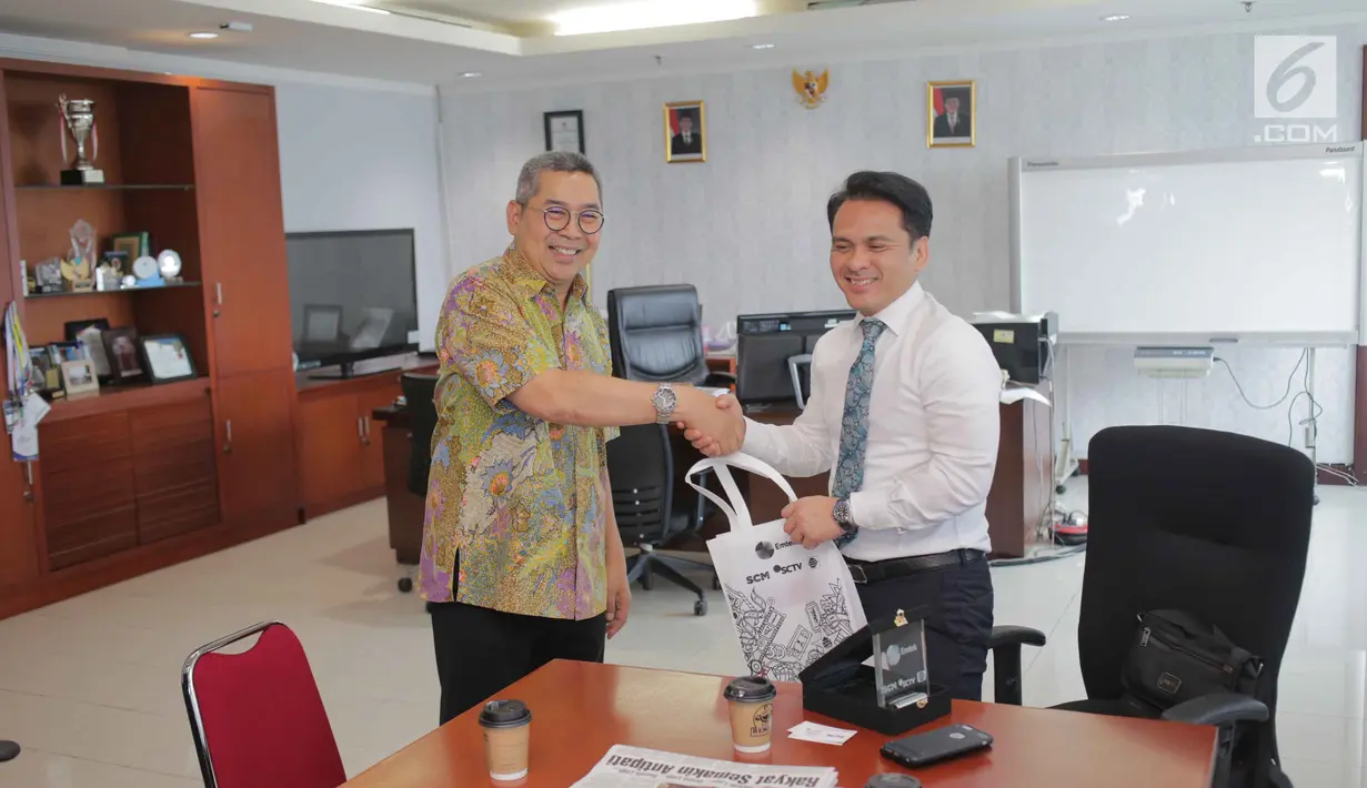 Sekretaris SCM Gilang Iskandar memberikan souvenir kepada Biro Komunikasi dan layanan Informasi Kementerian Keuangan Nufransa Wira Sakti usai beraudensi di Gedung Djuanda 1, Jakarta, Selasa (1/10/2019). Pertemuan tersebut membahas kerja sama di bidang sektor media. (Liputan6.com/Faizal Fanani)