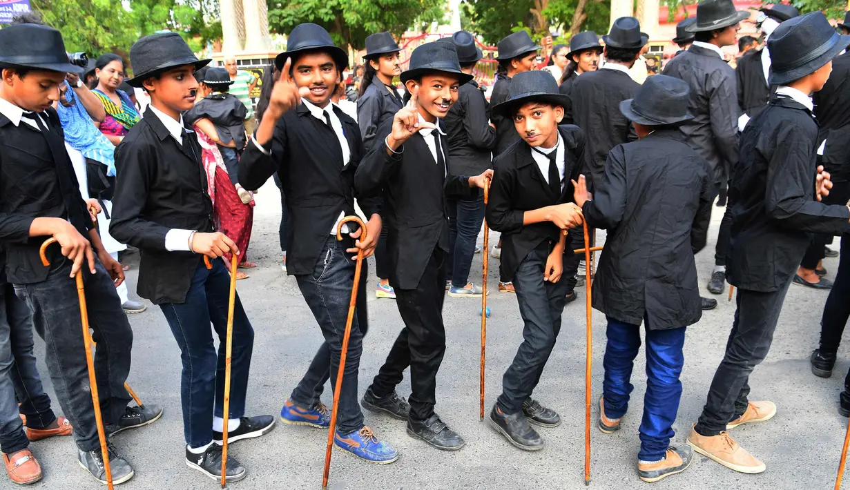 Sejumlah anak merayakan ulang tahun Charlie Chaplin di Adipur, India (16/4). Ratusan pengemar Charlie Chaplin mengenakan topi bowler dan kumis palsu membawa tongkat berjalan merayakan aktor komik tersebut. (AFP Photo/Indranil Mukherjee)