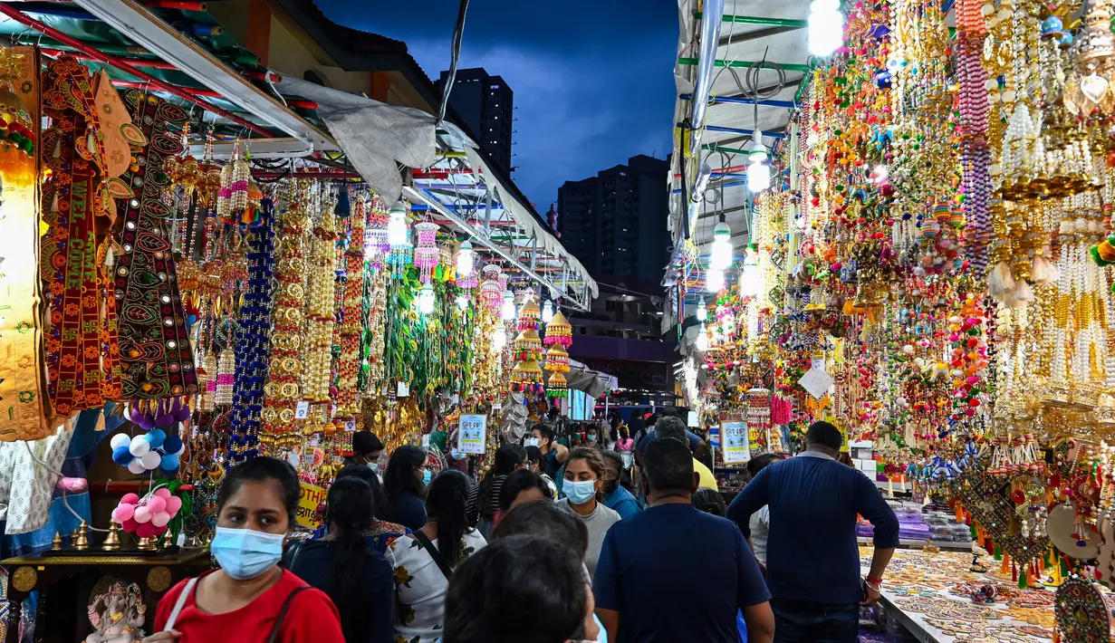 Orang-orang berjalan melintasi sepanjang toko yang menjual ornamen dan dekorasi menjelang Diwali, festival cahaya bagi umat Hindu, di distrik Little India di Singapura pada 23 Oktober 2020. (Photo by Roslan RAHMAN / AFP)