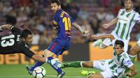 Lionel Messi (tengah) mengecoh kiper dan pemain Real Betis saat melakukan tembakan ke arah gawang pada lanjutan La Liga Spanyol di Camp Nou stadium, Barcelona, (20/8/2017). Barcelona menang 2-0. (AFP/Lluis Gene)