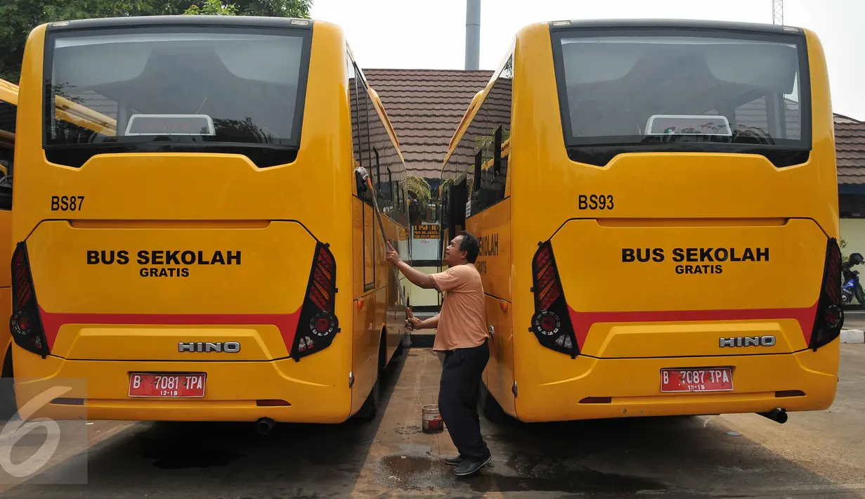 Pekerja membersihkan bus sekolah di Terminal Pasar Minggu, Jakarta, Senin (26/10). Gubernur DKI Basuki Tjahaja Purnama berencana menghapus keberadaan bus sekolah. Sebagai gantinya, pelajar akan digratiskan naik Transjakarta. (Liputan6.com/Gempur M Surya)