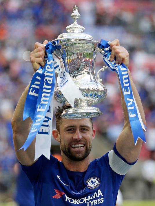 Bek Chelsea, Gary Cahill mengangkat trofi Piala FA usai pertandingan melawan Manchester United pada babak final Piala FA di stadion Wembley di London (19/5). Chelsea mengalahkan MU 1-0. (AP Photo / Tim Ireland)