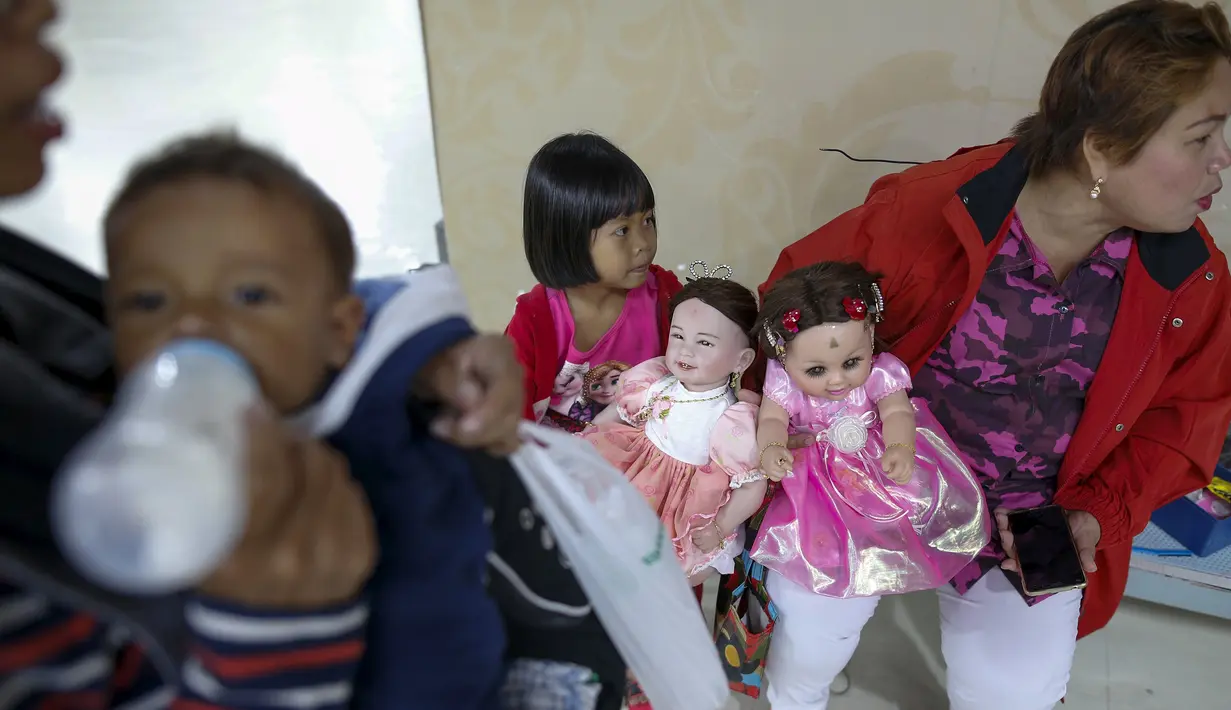 Warga menggendong boneka Look Thep (anak malaikat) di sebuah toko di department store, Bangkok, Thailand, Selasa (26/1). Boneka yang diisi dengan roh anak kecil melalui ritual tertentu itu dipercaya bisa membawa keberuntungan (REUTERS/Athit Perawongmetha)