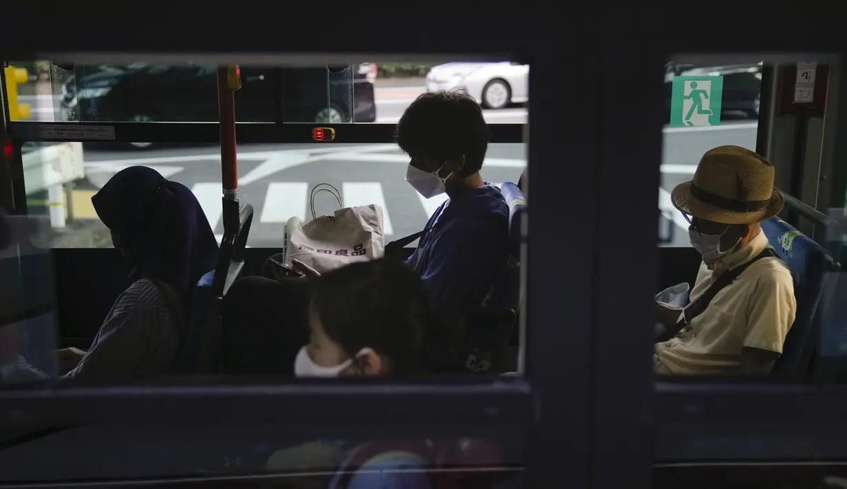 Komuter duduk di dalam bus menjelang Olimpiade Musim Panas 2020, di Tokyo pada 16 Juli 2021. Di bawah protokol yang ketat, satu-satunya cara untuk melihat sekilas ibu kota adalah dari kendaraan yang mengantar para tamu dari perkampungan atlet atau hotel ke venue. (AP Photo/Jae CHong)