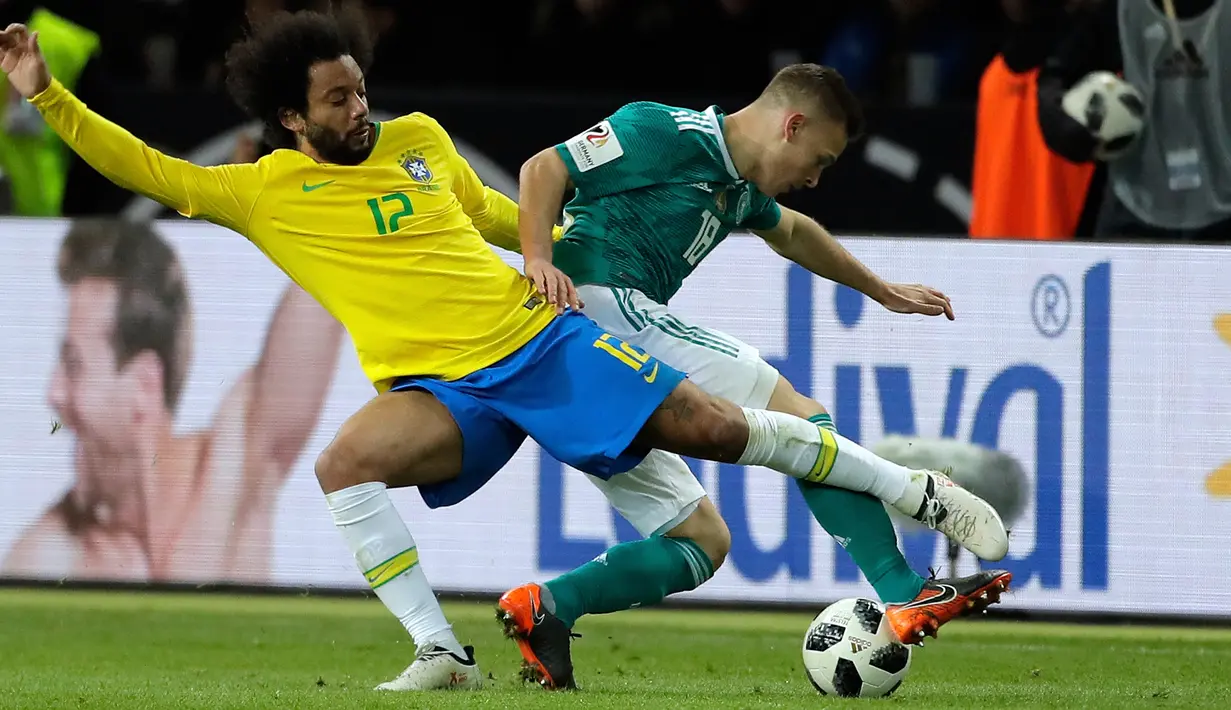 Pemain timnas Brasil, Marcelo berebut bola dengan pemain timnas Jerman, Joshua Kimmich pada laga uji coba di Olympiastadion Berlin, Selasa (27/3). Brasil sukses menaklukkan Jerman dengan skor 1-0. (AP Photo/Michael Sohn)