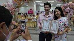 Petugas mengambil gambar pasangan dengan akta pernikahan mereka pada Hari Valentine di distrik Bang-Rak, Bangkok, Thailand, Senin (14/2/2022). Banyak pasangan menikah pada saat ini lokasi karena mereka percaya nama keberuntungannya akan membawa cinta yang tahan lama. (AP Photo/Sakchai Lalit)
