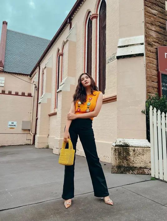 <p>Floral vest berwarna oranye dipadu padankan dengan celana highwaist berwarna hitam.&nbsp;(instagram/achasinaga)</p>