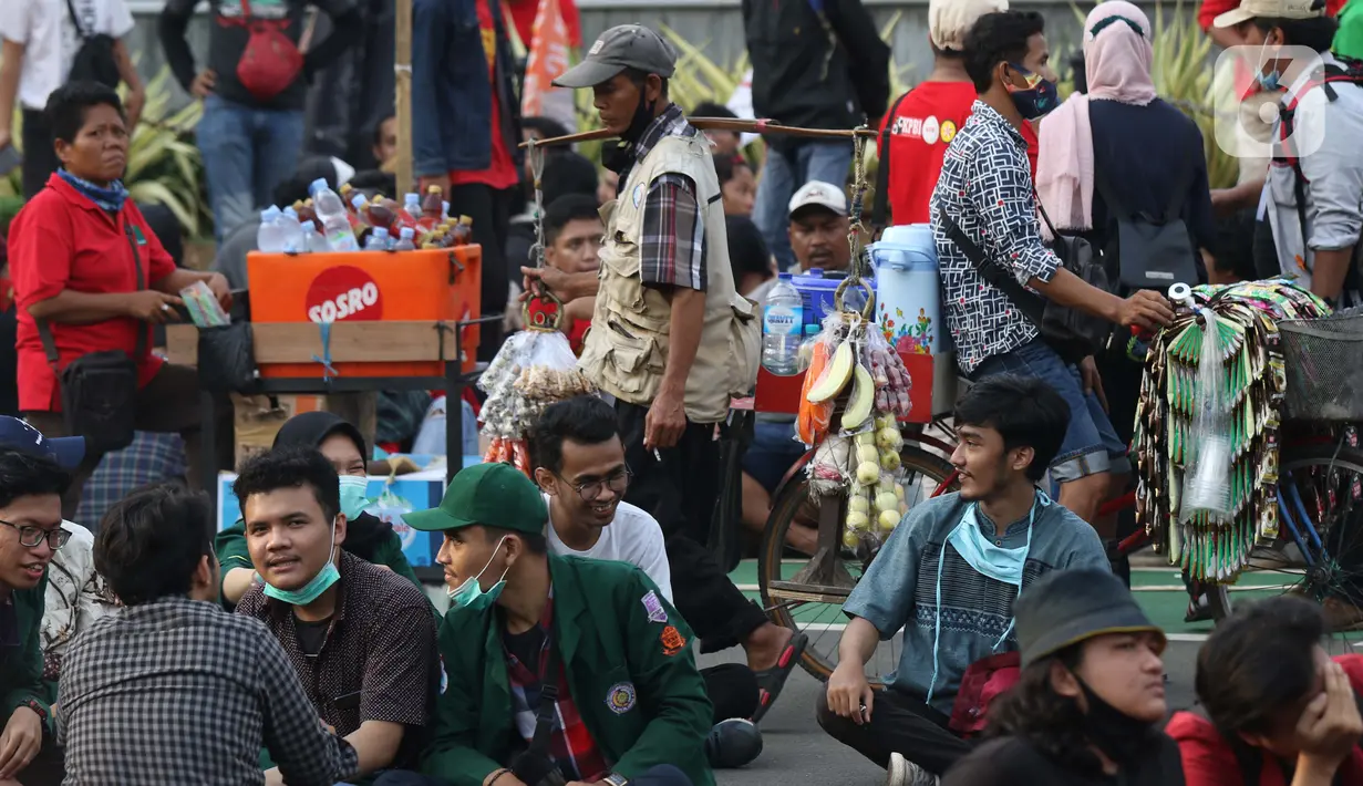 Pedagang asongan berjualan di tengah-tengah aksi unjuk rasa di kawasan Patung Kuda, Jakarta, Selasa (10/11/2020). Sejumlah pedagang mencoba peruntungan saat massa gabungan dari berbagai organisasi buruh dan mahasiswa berunjuk rasa menolak Omnibus Law UU Cipta Kerja. (Liputan6.com/Helmi Fithriansyah)