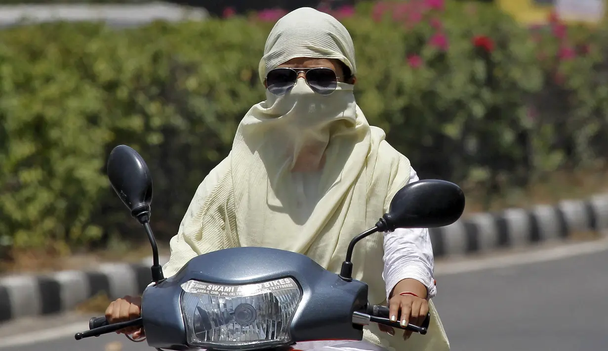 Seorang wanita mengendarai sepeda motor dengan wajah tertutup untuk melindungi diri dari sengatan matahari saat gelombang panas terjadi di India (28/5/2015). Dikabarkan 1.371 orang tewas karena suhu meningkat di atas 47 Celcius. (REUTERS/Ajay Verma)
