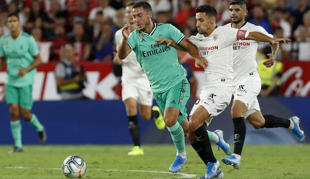 Gelandang Real Madrid, Eden Hazard menggiring bola dari kejaran pemain Sevilla, Daniel Carrico pada pertandingan lanjutan La Liga Spanyol di stadion Ramon Sanchez Pizjuan di Seville (22/9/2019). Real Madrid menang tipis atas Sevilla 1-0. (AP Photo/Miguel Morenatti)