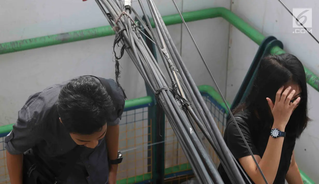Pejalan kaki melintasi jembatan penyeberangan orang yang terhalang instalasi kabel di Depok, Jawa Barat, Sabtu (8/12). Selain mengganggu kenyamanan, keberadaan instalasi kabel semrawut tersebut membahayakan pejalan kaki. (Liputan6.com/Immanuel Antonius)