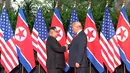 Presiden AS Donald Trump  berjabat tangan dengan Pemimpin Korea Utara, Kim Jong-un dalam pertemuan bersejarah di resor Capella, Pulau Sentosa, Selasa (12/6). Trump dan Kim berjabat tangan untuk pertama kalinya. (Host Broadcaster Mediacorp Pte Ltd via AP)