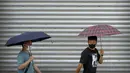 <p>Komuter mengenakan masker dan membawa payung berjalan selama jam sibuk pagi hari pada hari hujan di Beijing, Rabu (29/6/2022). China memangkas lama karantina wajib bagi pelancong luar negeri dari 21 hari menjadi tujuh hari ditambah tiga lagi pemantauan di rumah. (AP Photo/Mark Schiefelbein)</p>