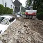 Sebuah mobil tertimbun puing-puing setelah hujan lebat menyebabkan banjir dan kerusakan besar di distrik Hohenlimburg di Hagen, Jerman, Kamis (15/7/2021). (Julian Stratenschulte/dpa via AP)