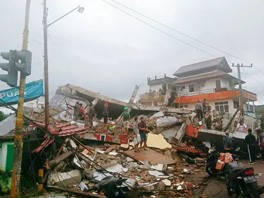 Warga memeriksa bangunan yang rusak akibat gempa di Mamuju, Sulawesi Barat, Indonesia, Jumat (15/1/2021). Sejumlah rumah dan bangunan di Mamuju roboh akibat gempa dengan berkekuatan 6,2 skala Richter yang berpusat di timur laut Majene. (AP Photo/Rudy Akdyaksyah)