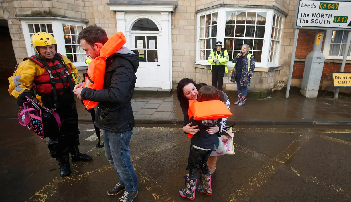Petugas mengevakuasi warga yang terjebak banjir dirumahnya di Tadcaster, Inggris utara, Minggu (27/12). Banjir akibat luapan sungai Ouse yang telah memperburuk sejumlah wilayah Inggris utara. (REUTERS/Andrew Yates)