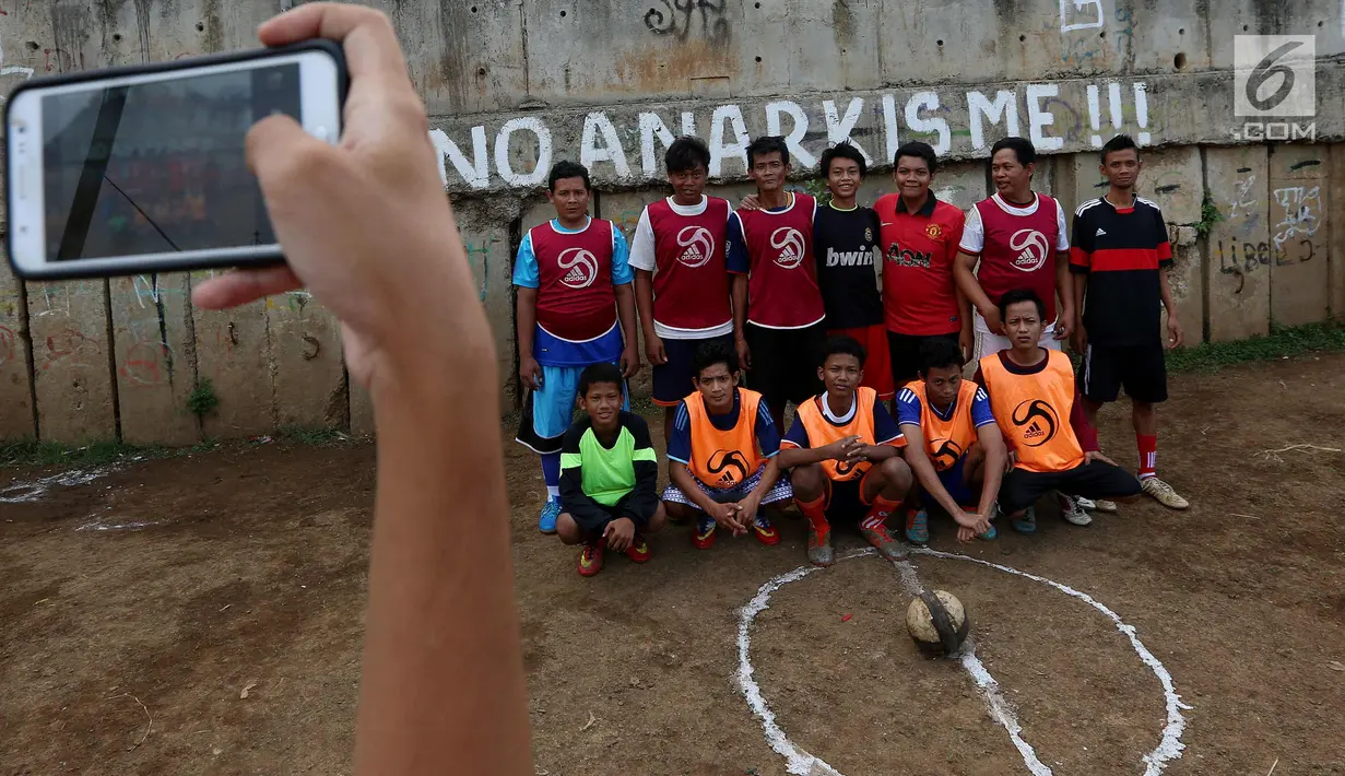 Warga melakukan foto bersama sebelum kompetisi sepak bola di pinggir Kali Banjir Kanal Barat, Jakarta, Sabtu (5/11). Minimnya sarana bermain sepak bola mengakibatkan warga terpaksa memanfaatkan lahan di pinggir kali. (Liputan6.com/Johan Tallo)