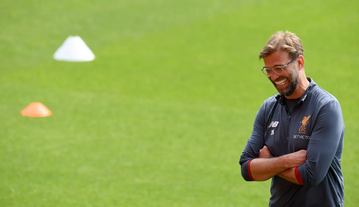 Pelatih Liverpool, Jurgen Kloop tertawa saat melihat para pemainnya berlatih di stadion Anfield, Inggris (21/5). Liverpool akan bertanding melawan wakil Spanyol, Real Madrid pada babak Final Liga Champions. (AFP Photo/Paul Ellis)