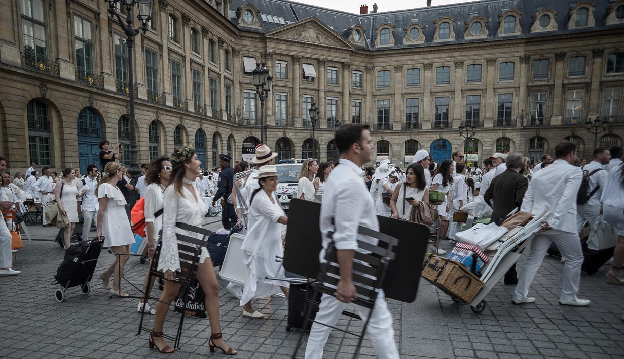 Peserta membawa kursi dan perlengkapan lain ketika mengikuti 'Diner en blanc' atau 'Makan Malam Putih' di Place Vendome, Paris, Rabu (8/6). Untuk  mendapatkan undangan, peserta harus mengenal seorang anggota organisasi Diner en Blanc. (PHILIPPE LOPE/AFP)