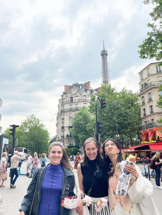 Raline Shah mengenakan set kemeja dan celana putih bermotif bunga besar sambil menikmati baguette [@ralineshah]