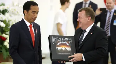 Perdana Menteri Denmark Lars Lokke Rasmussen memberikan Presiden Joko Widodo (Jokowi) cendera mata piringan hitam band Metallica usai pernyataan bersama dalam kunjungan kerja PM Denmark di Istana Bogor, Jawa Barat, Selasa (28/11). (AP/Dita Alangkara)