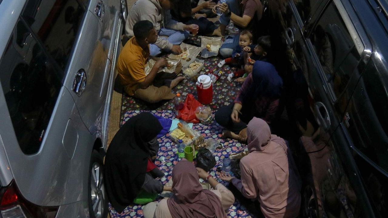Pemudik menggelar tikar dan menyantap hidangan berbuka puasa di antara mobil yang terparkir di rest area Tol Cipalo KM 102, Subang, Jawa Barat, Sabtu (6/4/2024).&nbsp;Pada puncak arus mudik Lebaran, rest area di sepanjang Tol Trans Jawa menjadi tempat fav