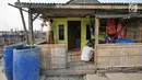 Warga memperbaiki talang yang menyalurkan air ke dalam tong di rumahnya, Kampung Kamal Muara, Jakarta, Selasa (9/7/2019). Sebagian besar warga Kampung Kamal Muara memasang pipa pada talang air di tepi atap rumah mereka untuk menampung air hujan. (Liputan6.com/Herman Zakharia)