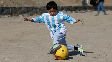 Murtaza Ahmadi (5), bocah asal Afghanistan, memakai jersey yang ditandatangani langsung oleh bintang Barcelona yang juga idolanya, Lionel Messi, ketika bermain sepak bola di sebuah lapangan terbuka di Kabul, Jumat (26/2). (REUTERS/Omar Sobhani)