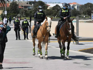 Polisi berpatroli dengan menunggang kuda di sepanjang St Kilda Esplanade di Melbourne (26/10/2020). Pejabat kesehatan Australia melaporkan tidak ada kasus virus corona baru atau kematian di negara bagian Victoria. (AFP Photo/William West)