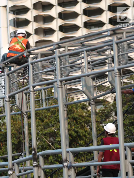Pekerja menyelesaikan revitalisasi Jembatan Penyeberangan Orang (JPO) Gelora Bung Karno (GBK), Jakarta, Selasa (27/11). Pembangunan tiga JPO Polda Metro Jaya, GBK dan Bundaran Senayan menelan Rp56 miliar. (Liputan6.com/Faizal Fanani)