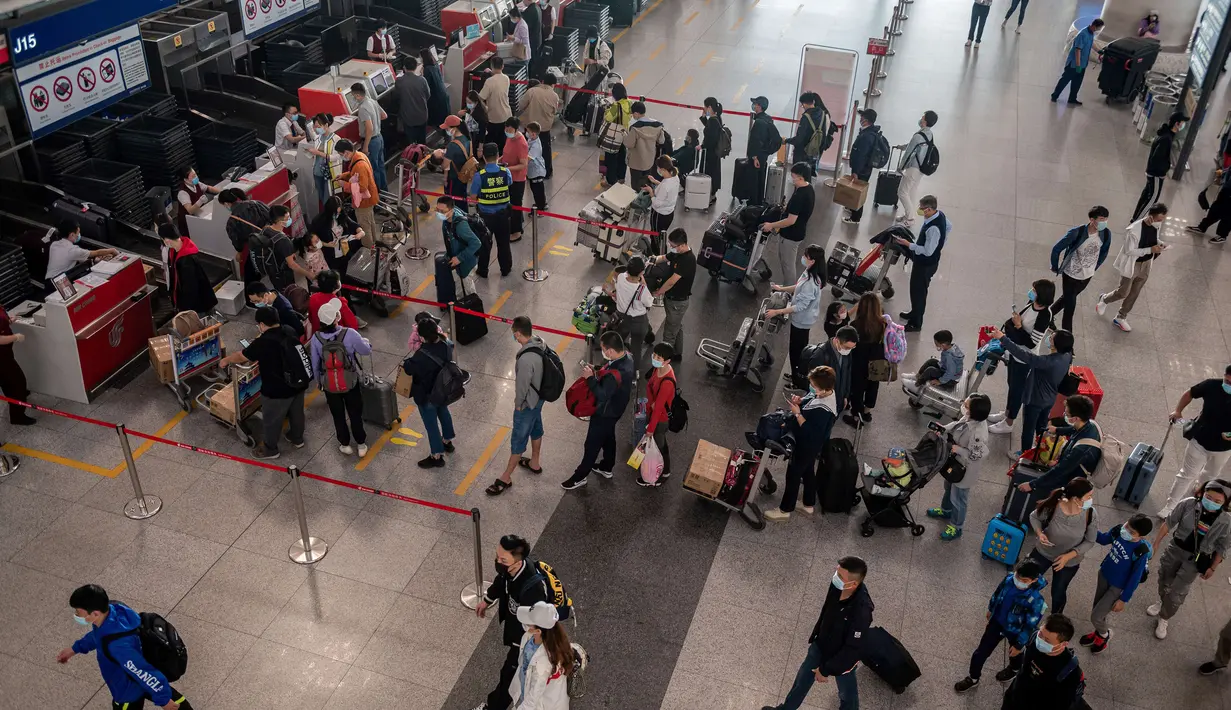 Orang-orang mengantre check-in untuk penerbangan domestik menjelang liburan "Golden Week" di Bandara Internasional Ibu Kota Beijing pada 30 September 2020. Gelombang liburan melanda China yang warganya merayakan libur panjang, yang dikenal dengan Golden Week. (NICOLAS ASFOURI / AFP)