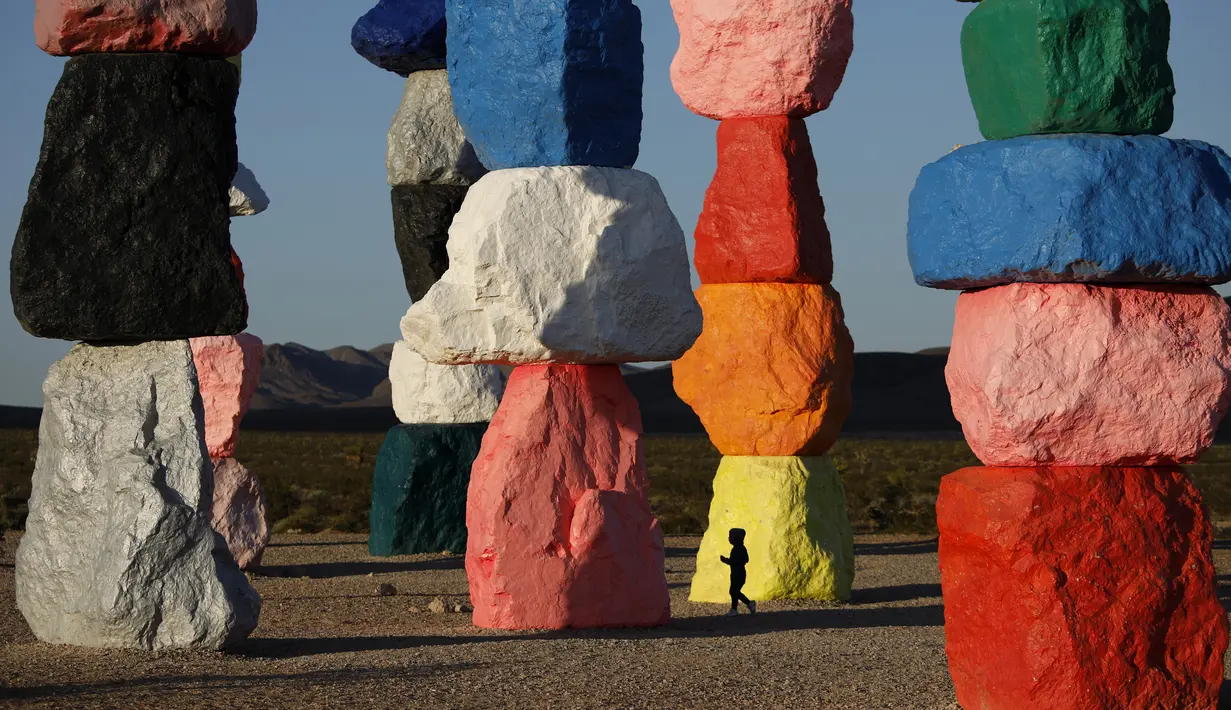 Seorang anak berlari melewati instalasi seni Seven Magic Mountains karya seniman Ugo Rondinone di Las Vegas, Amerika Serikat, Selasa (7/4/2020). Susunan batu berwarna neon memungkinkan Anda untuk mengambil foto-foto yang sangat menarik. (AP Photo/John Locher)