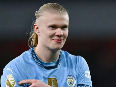 Pemain Manchester City memamerkan badge trofi Premier League kehadapan fans Arsenal. Hal itu dilakukan bomber asal Norwegia untuk membalas ejekan fans The Gunners. (AFP/Glyn Kirk)