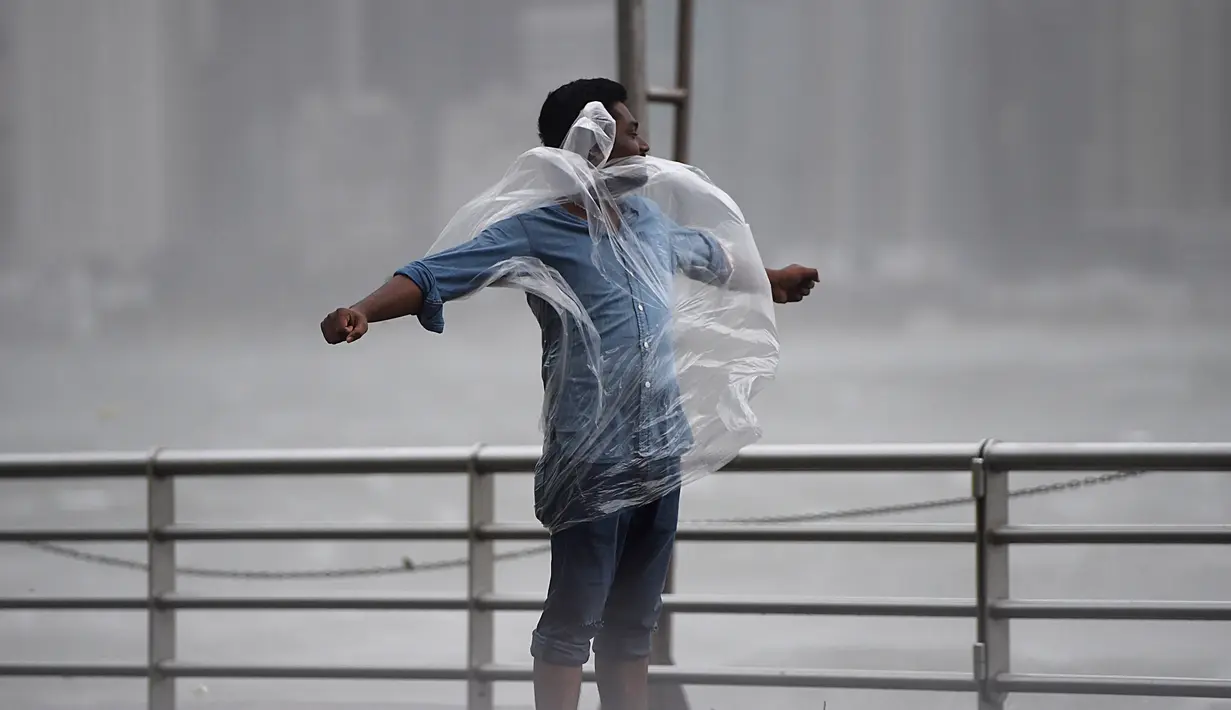 Seorang pria berdiri melawan angin kencang dan hujan yang ditimbulkan oleh Topan Hato di Hong Kong (23/8). Terjangan topan Hato mengakibatkan lebih dari 400 penerbangan dibatalkan. (AFP/Anthony Wallace)