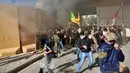 Tentara AS menembakkan gas air mata ke arah demonstran yang masuk ke kompleks kedutaan AS, di Baghdad, Irak (31/12/2019). Serbuan ini dilakukan para demonstran yang marah atas serangan udara AS terhadap milisi Irak yang disebut pro-Iran. (AP Photo/Khalid Mohammed)